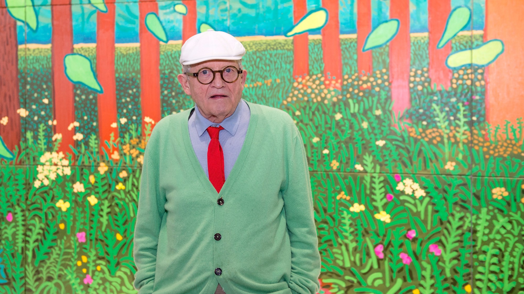 David Hockney poses in front of his painting "The Arrival Of Spring in Woldgate, East Yorkshire in 2011"