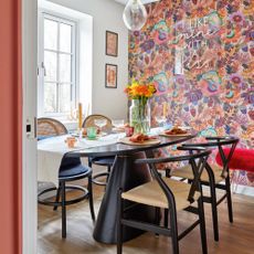 Modern-style dining table with wishbone chairs and floral pink wallpaper