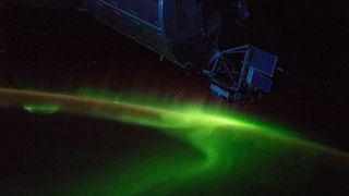 A lime-green aurora lights up Earth's atmosphere over the Indian Ocean in this photo captured from the International Space Station. In the foreground is the Columbus module, a research laboratory that the European Space Agency launched to the station in 2008.