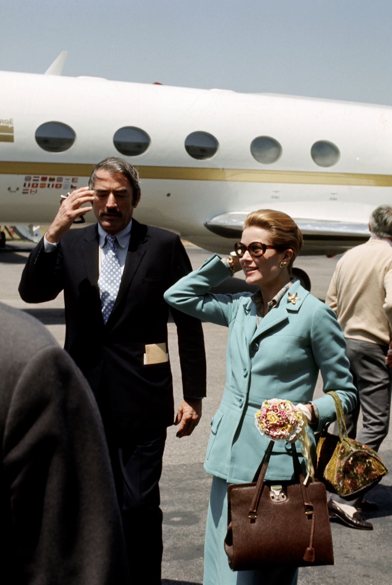Grace Kelly and Gregory Peck in front of a small white aircraft