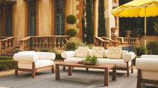 outdoor living room with cream sofa, yellow stripe cushions, and yellow parasol
