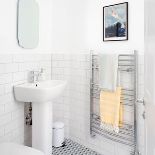 bathroom with white tiles, towel hanger, washbasin & walled photo frame