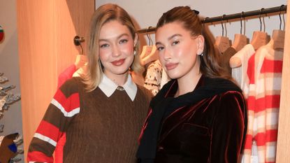 Gigi Hadid in a brown and red Guest in Residence Striped Rugby and Guest in Residence brown cashmere vest and Hailey Bieber in a burgundy velvet skirt and jacket at the Guest in Residence store opening in Los Angeles.