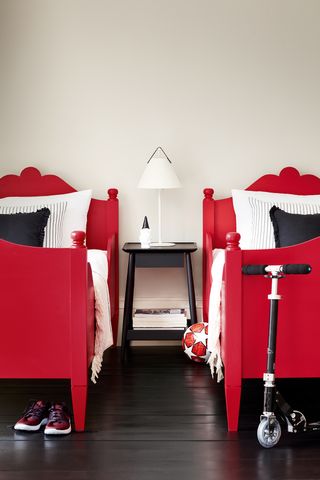 two twin beds painted red, black floor, white walls, scooter
