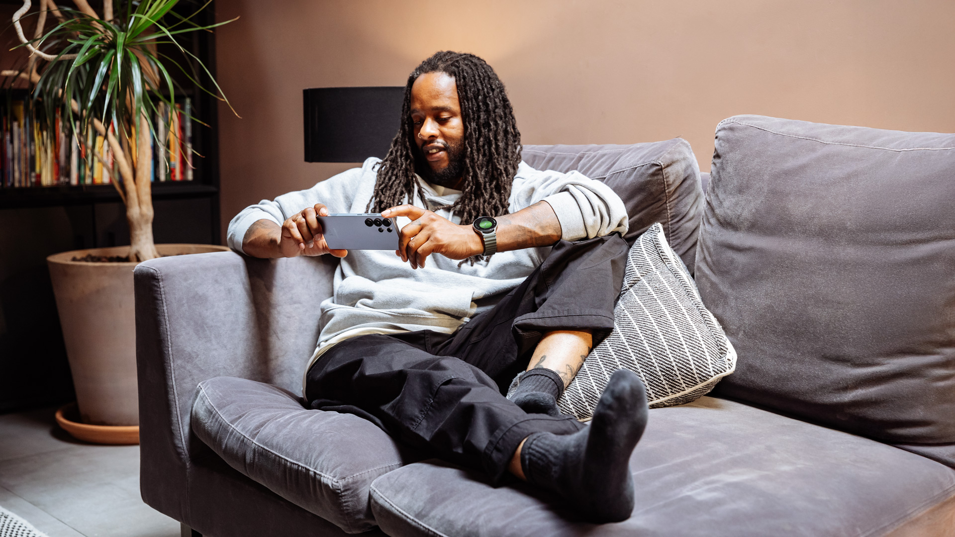A man sat on a sofa watching a film on the Samsung Galaxy S25 Ultra.
