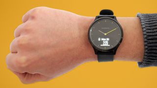 A garmin vivomove hr on someone's wrist with a yellow background