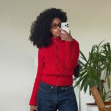 a woman wearing a red cardigan and jeans