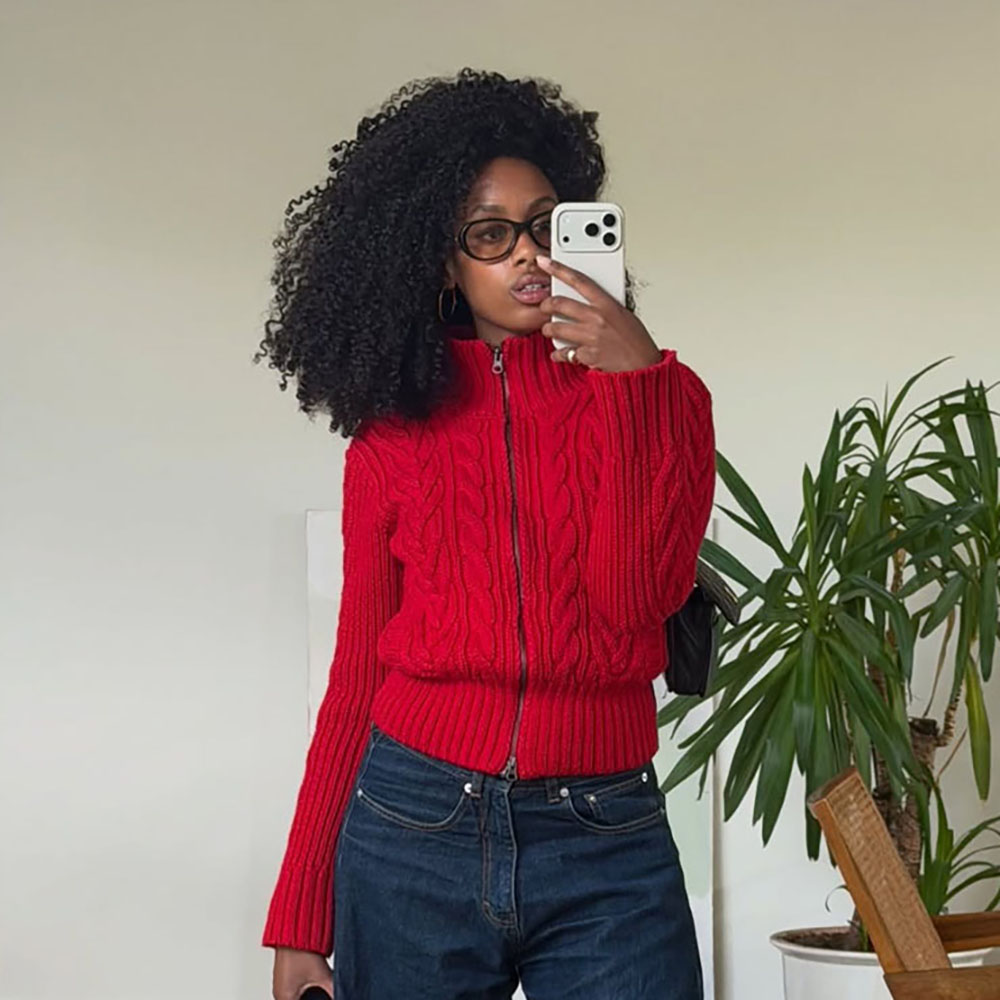 a woman wearing a red cardigan and jeans