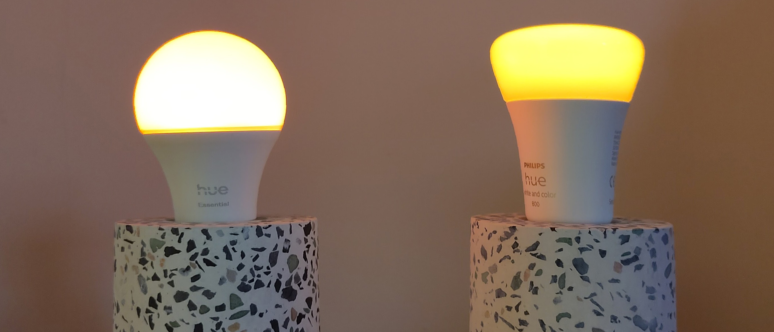 Philips Hue Essential bulb next to Philips Hue White &amp; Color Ambiance bulb, both on dimmest setting