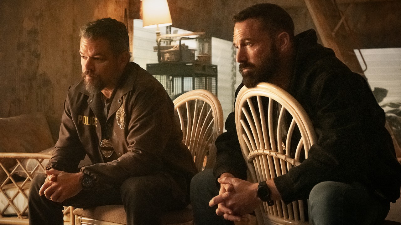 From left to right: Matt Damon and Ben Affleck sitting in chairs with their hands clasped together. 
