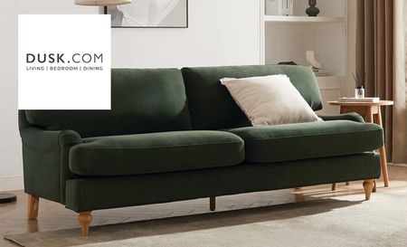A dark green couch with brown legs and a cream cushion placed on top of it