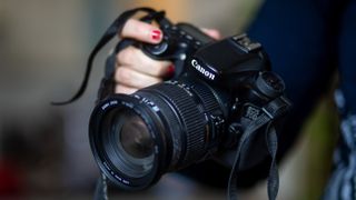 A hand holding the Canon EOS 80D DSLR