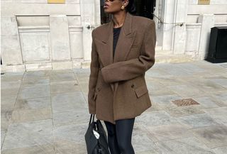 Marilyn Nwawulor-Kazemaks wears a brown blazer, leggings, and black slingback flats.