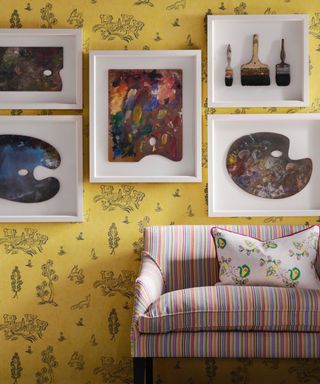 living room with yellow wallpaper, striped couch, floral couch pillow, bold artwork