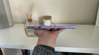 Amazon Fire HD 10 (2023) tablet held in hand showing side edge in front of white shelf