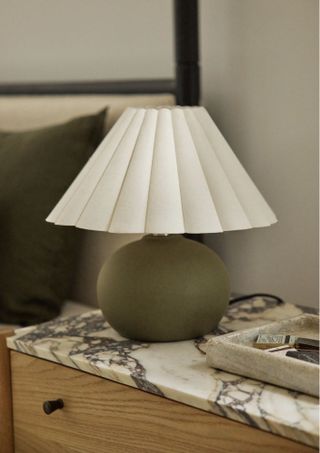 small table lamp with dark green base and white pleated shade