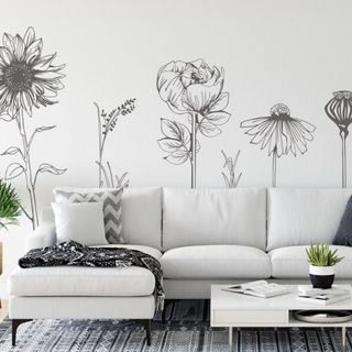 White living room with vinyl flower wall sticker decals and a white sofa with a white coffee table on top of a black and white patterned carpet