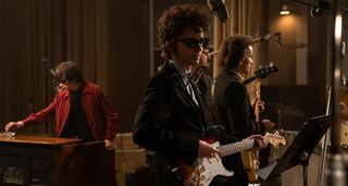 Timothée Chalamet as Bob Dylan in a still from A Complete Unknown: In this studio scene, Chalamet's Dylan is playing his Fender Stratocaster in the studio, wearing dark sunglasses, anticipating the moment he turns folk electric at Newport.