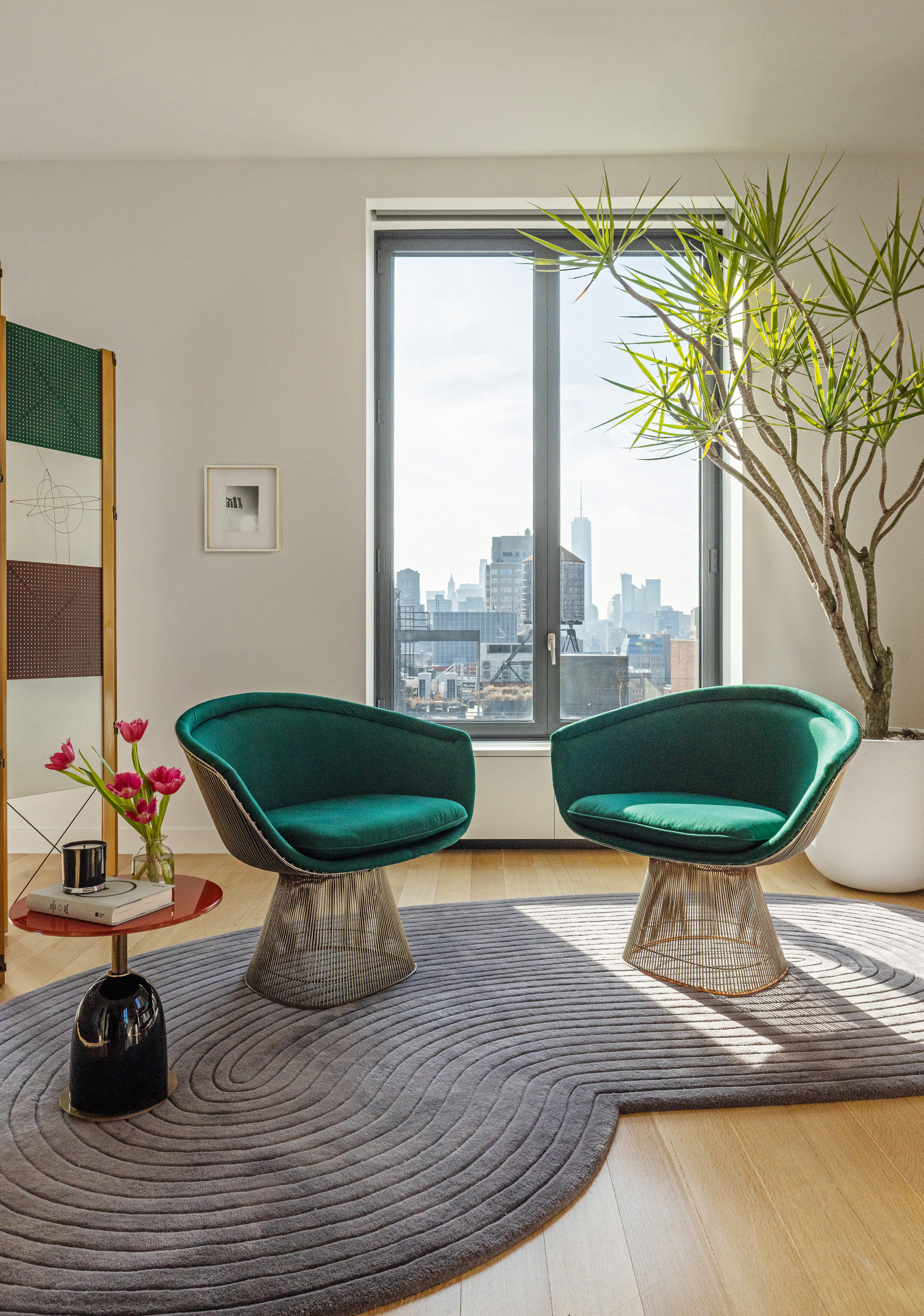 Living room with emerald armchairs, grey shaped rug and red and black glossy side table
