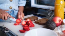 Woman chopping up berries and strawberries, the best fruit for weight loss