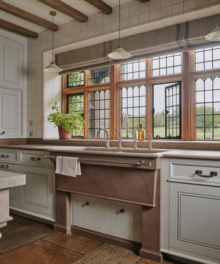 A historic home with a large kitchen with the sink placed beneath large windows