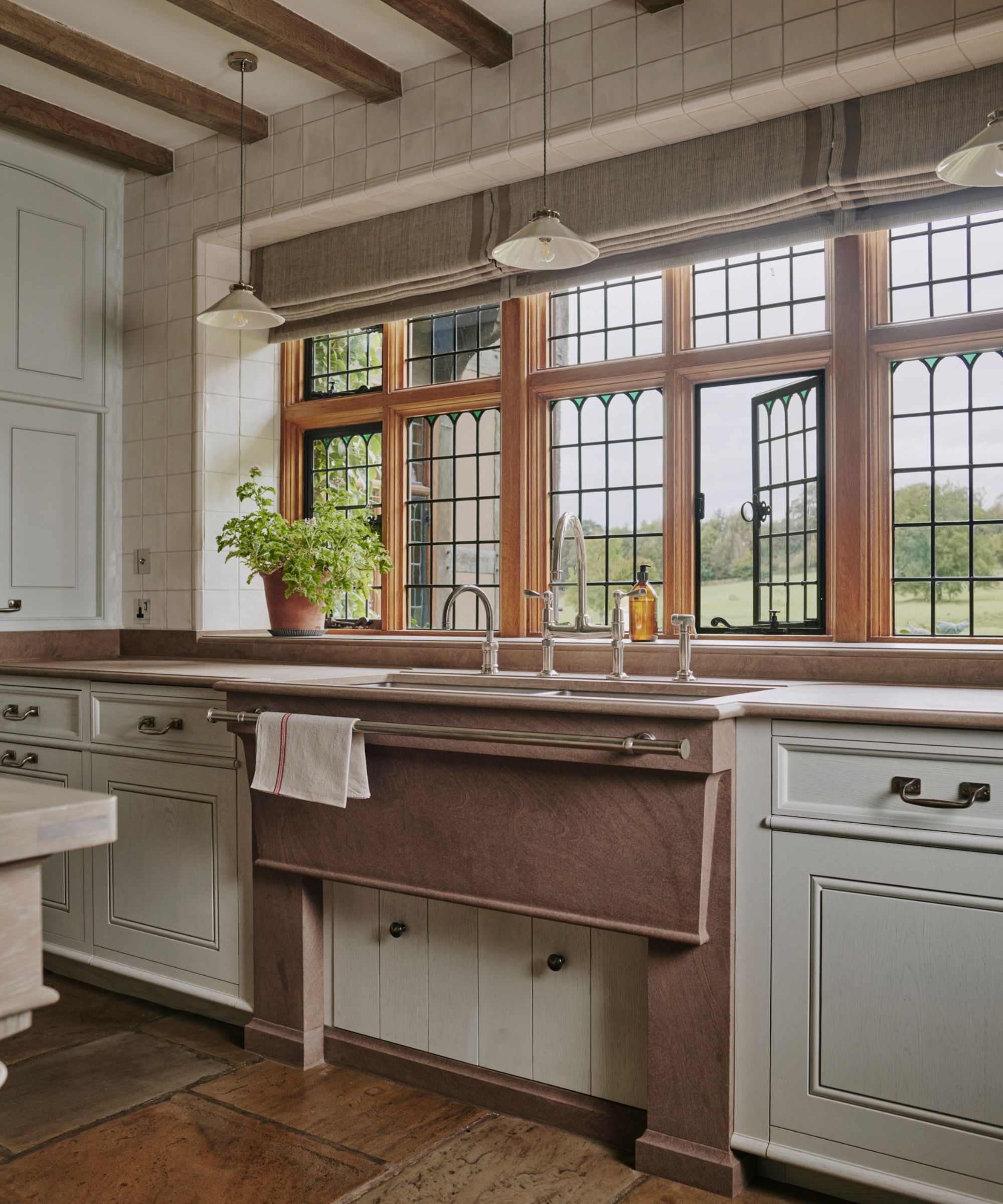 A historic home with a large kitchen with the sink placed beneath large windows