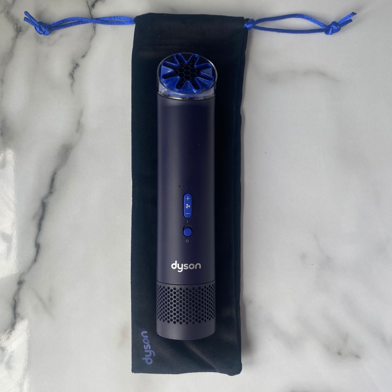 Dyson HushJet Mini Cool fan laid on top of the travel pouch on a marble look worktop