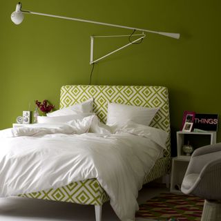 green bedroom with white duvet cover and patterned headboard