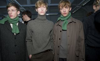 3 male models wearing muted colours with green scarfs.
