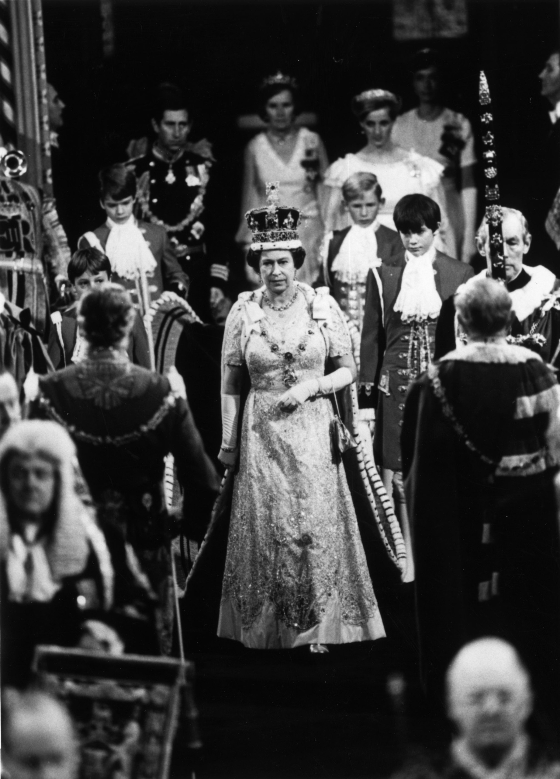 Queen Elizabeth walking with her crown at the state opening of Parliament 1984 and Prince Charles and Princess Diana following behind her