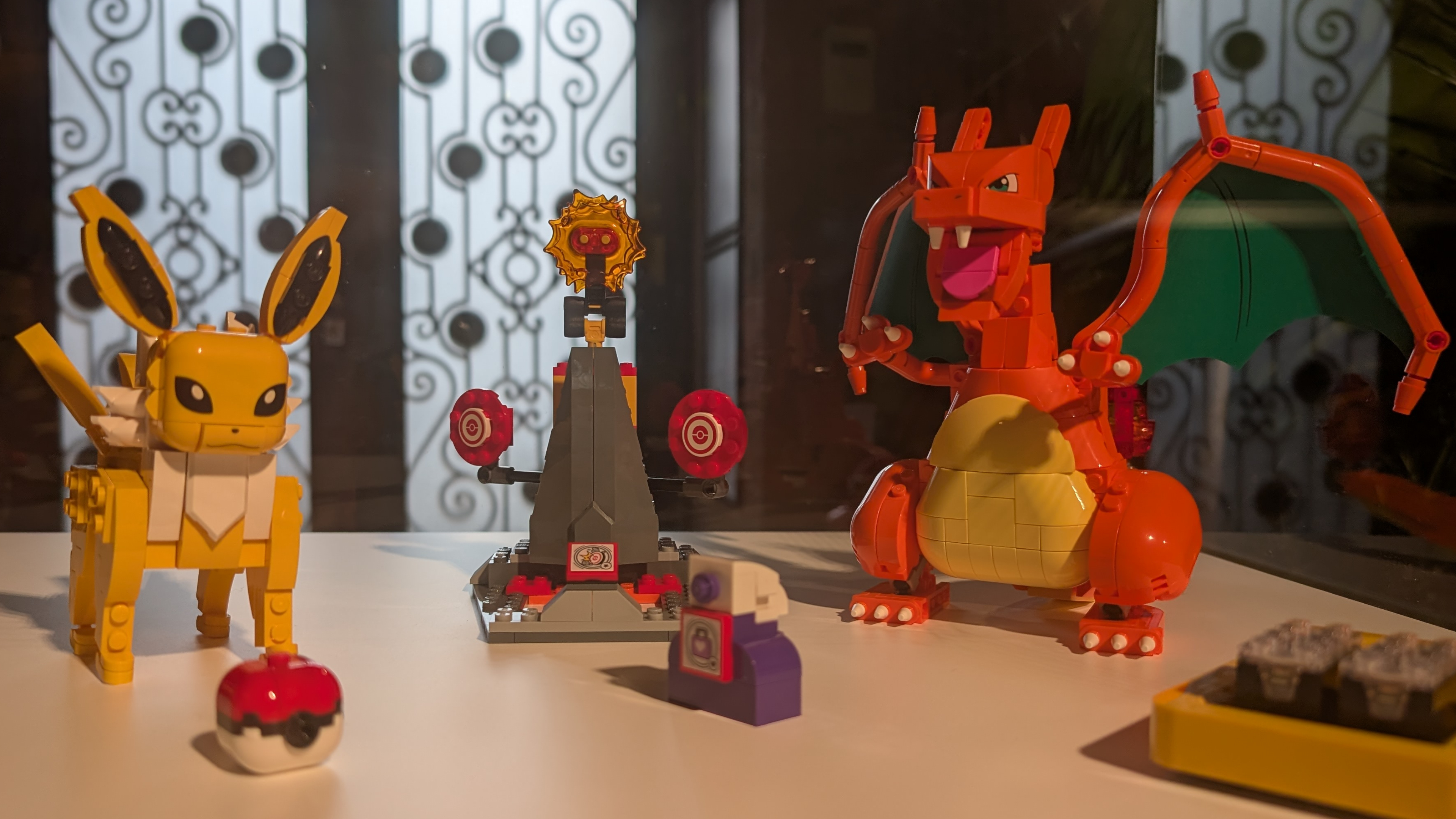 Jolteon and Charizard on a white surface, beside accessories