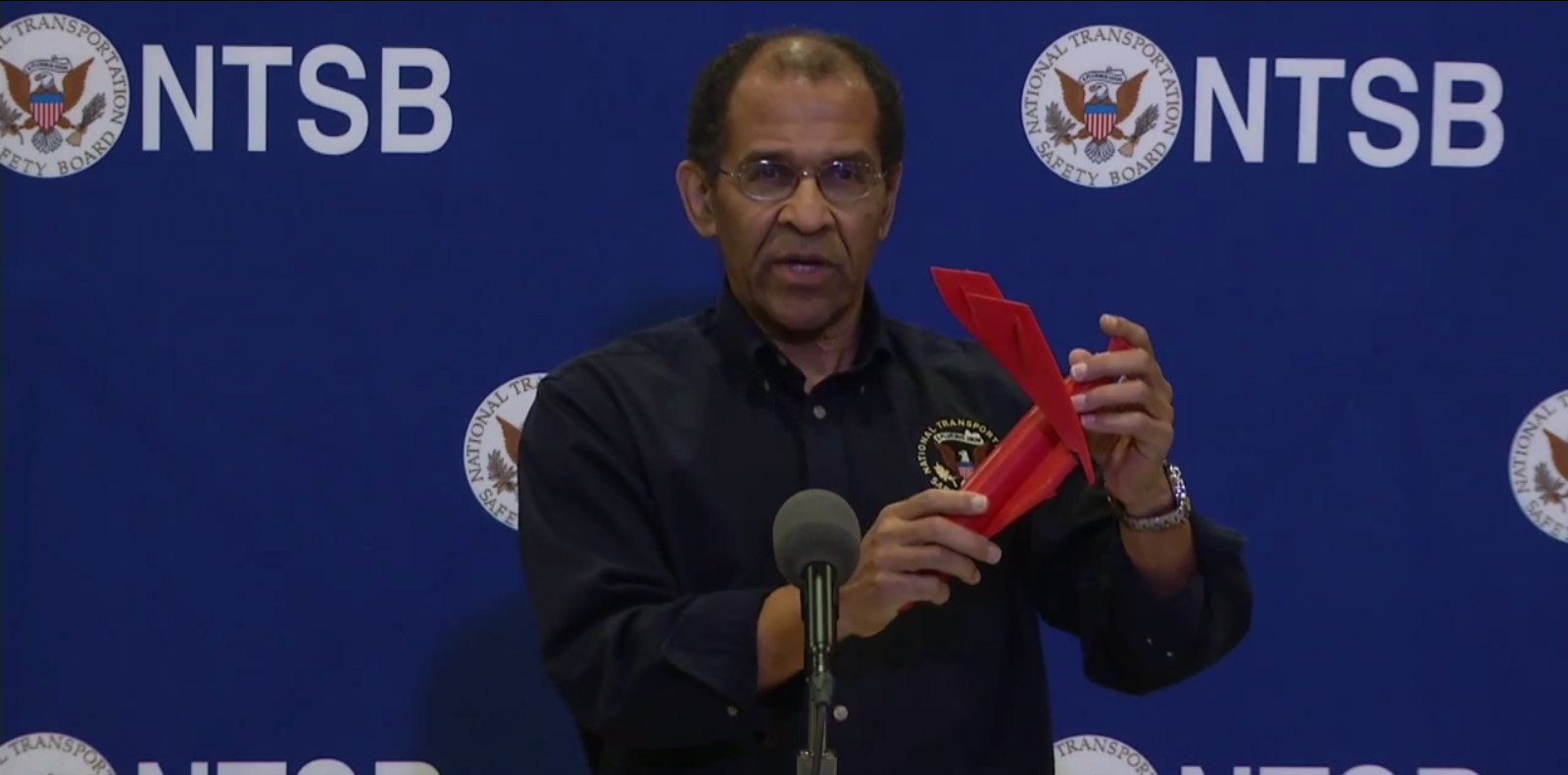 Christopher Hart, Acting Chairman of the National Transportation Safety Board, holds a model of Virgin Galactic&#039;s SpaceShipTwo space plane with its twin tail booms in the &quot;feathered&quot; position. Hart said Nov. 2 that SpaceShipTwo&#039;s feathering descent system