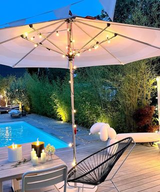 A pool deck with parasol and fairy lights