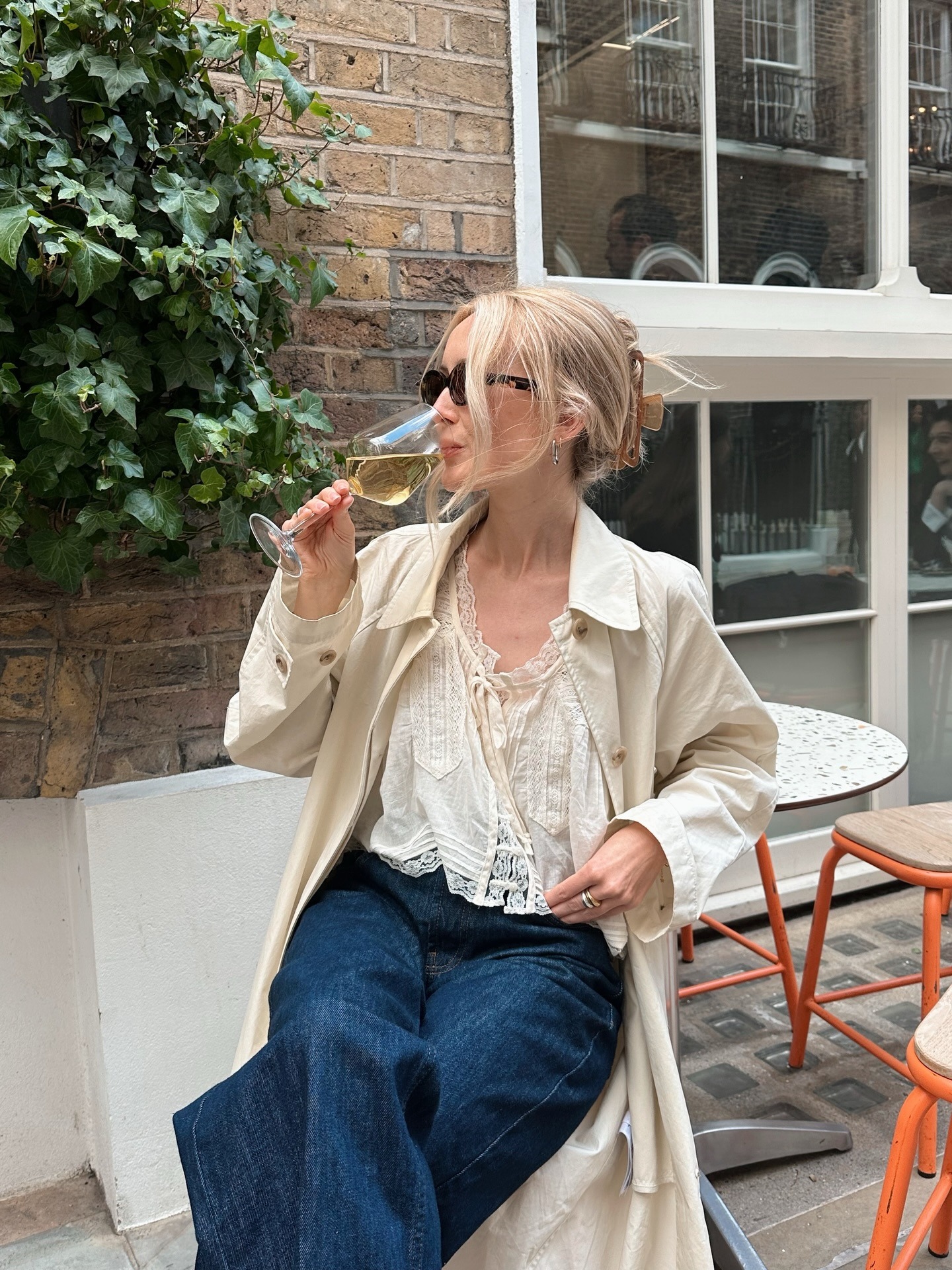 Woman wears blouse, trench coat, jeans