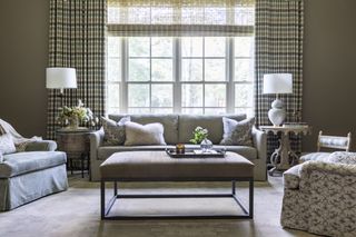 Living room with shade, striped curtains, sofa and armchairs in neutral palette