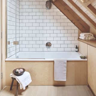 A wood-panelled bathroom with a white-tiled bath/shower area