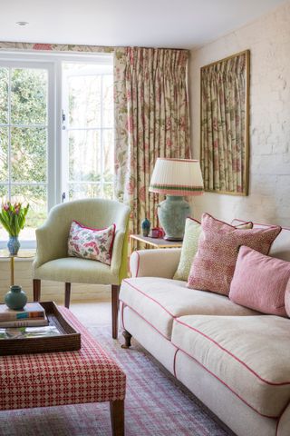 pink and green living room, with floral drapes, couch and green and pink cushions, green armchair, pleated shade lamp