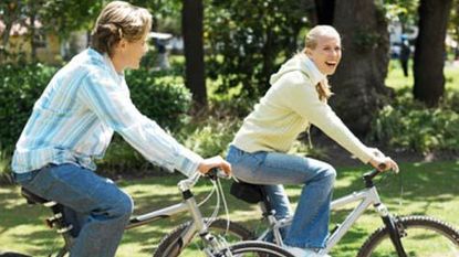 couple riding bikes together through a park