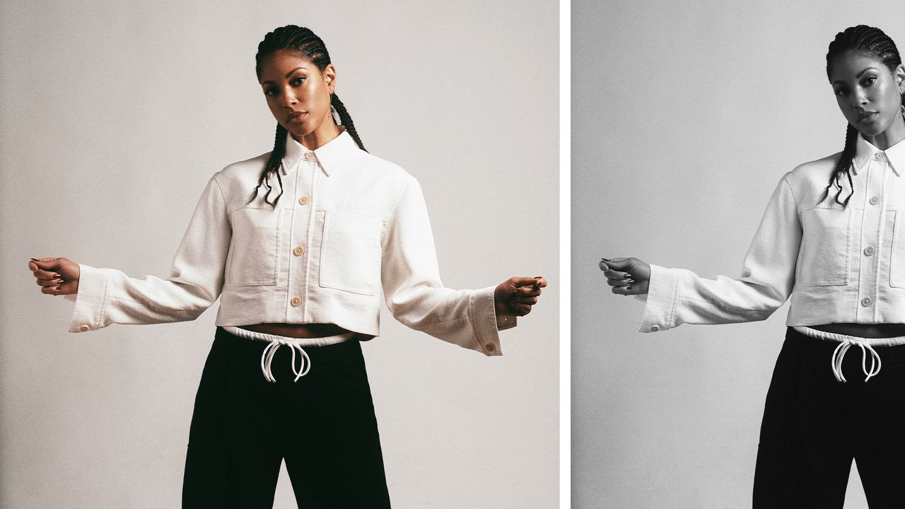 Lex Scott Davis poses wearing a white cropped button-down jacket and black trousers with a white tie. 