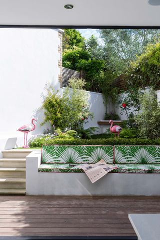 Small garden with built in bench and flamingo decor