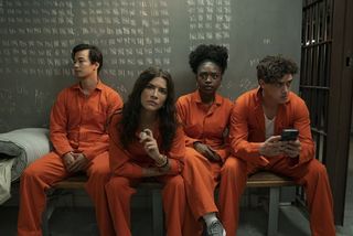 Fire unge sidder i orange fangedragter i en celle