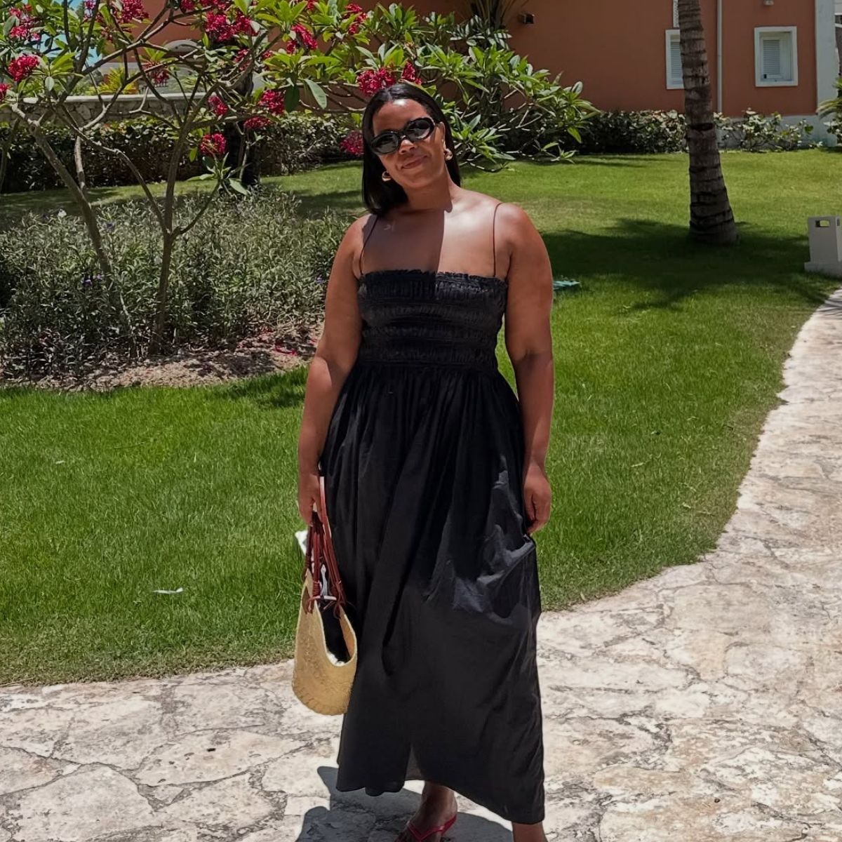 Woman wears shirred dress, basket bag and red flip flops