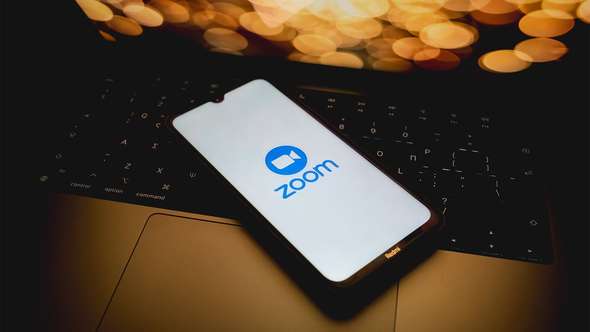 Logo of Zoom, developer of the Zoom Docs platform, pictured on a smartphone with blurred lights in background.