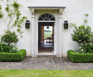 A front door open to a house and a garden in the background