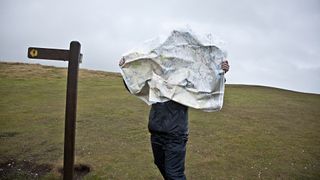一个徒步旅行者在风中挣扎着他的地图
