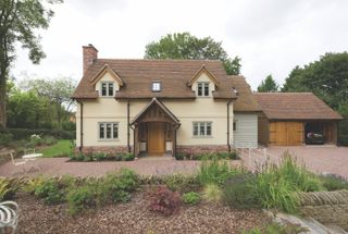 cream coloured cottage built using oak frame with porch and garage