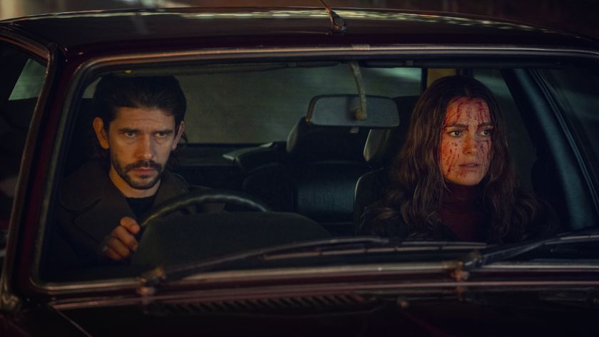 Sam and Helen sitting in a car looking shocked at something off camera. Helen&#039;s face is covered in blood.