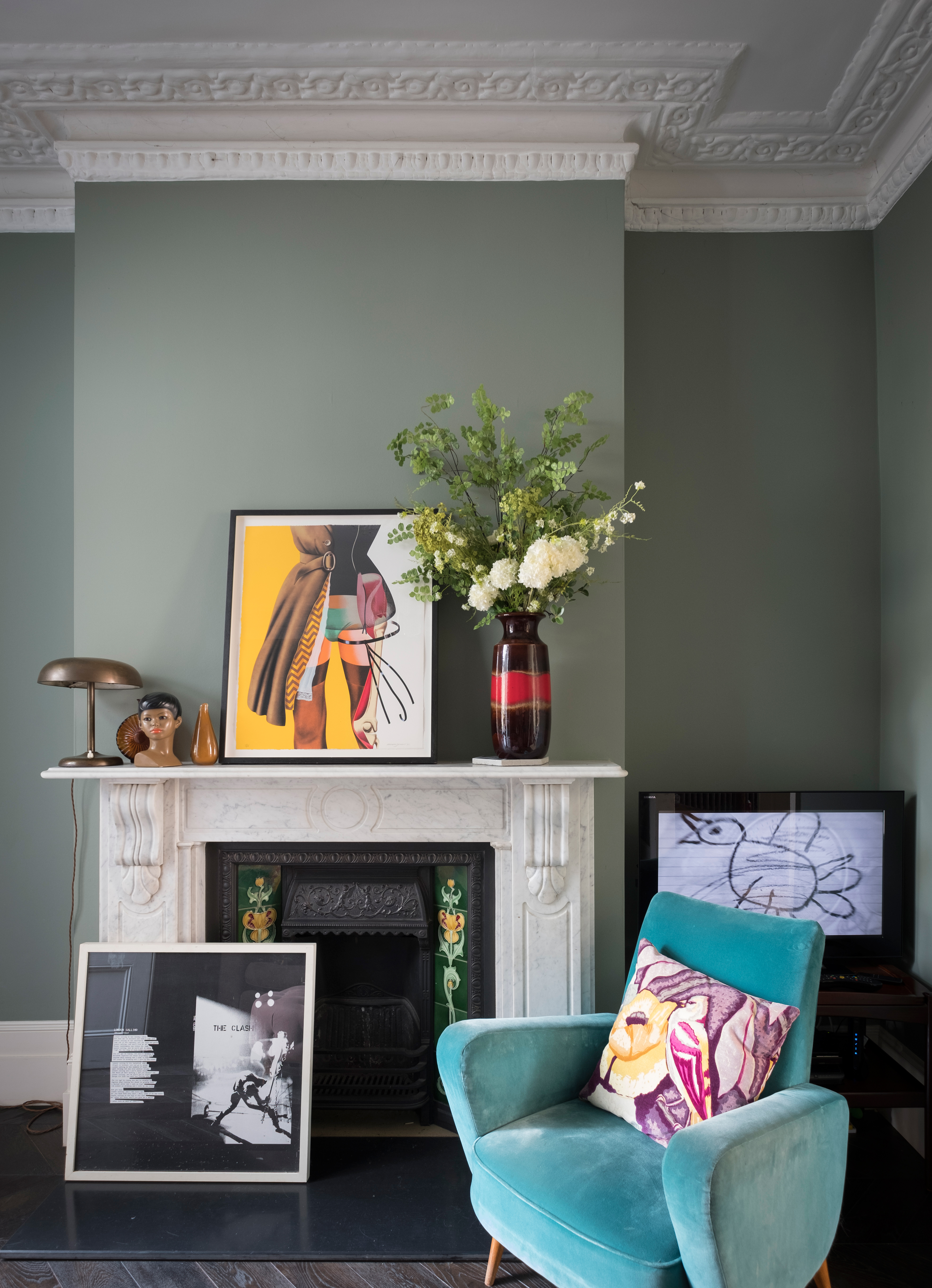 Green living room with white fireplace with blue velvet chair