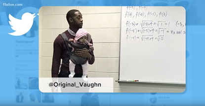 Prof. Nathan Alexander holds his student's daughter as he teaches.