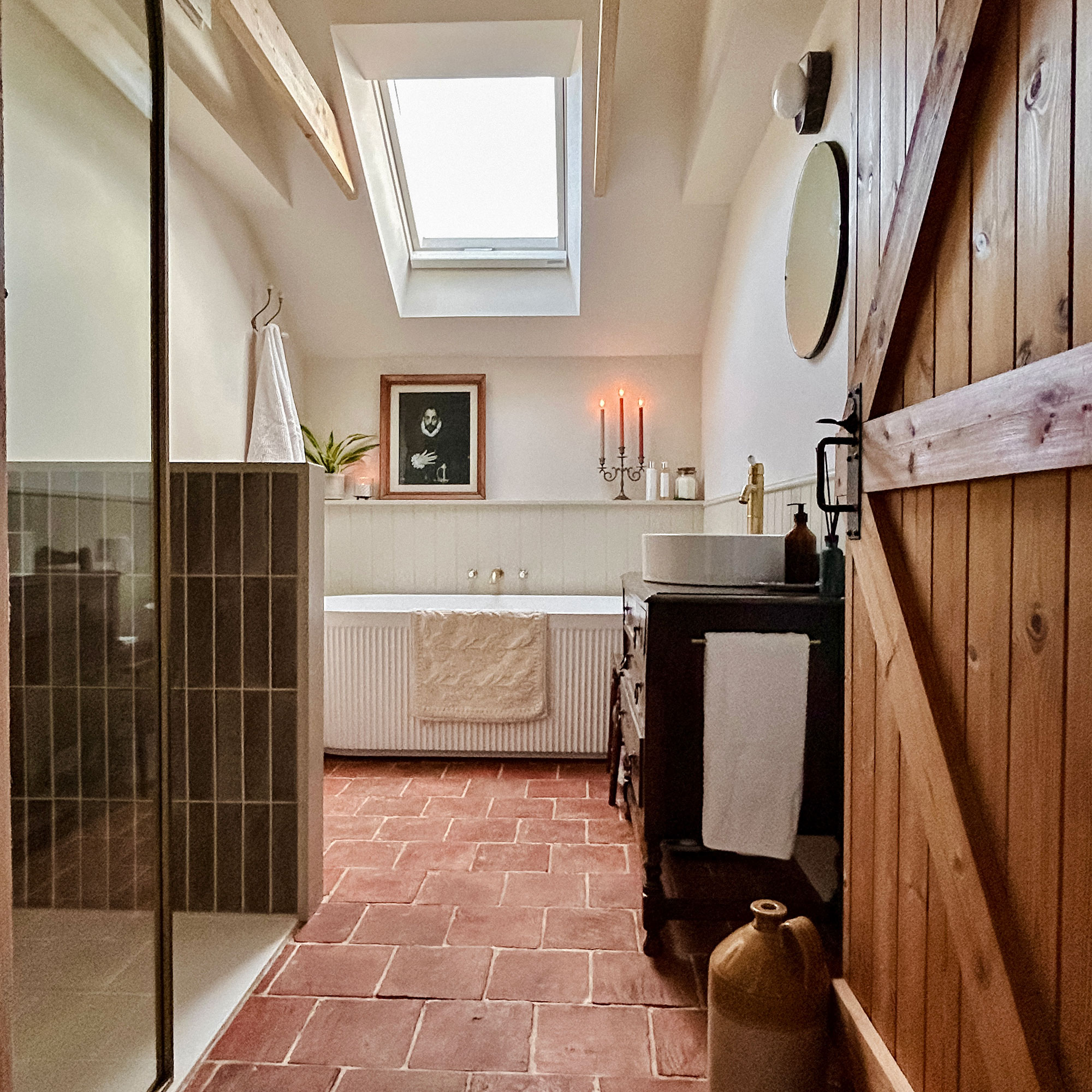 Bathroom with terracotta floors and skylight above bath